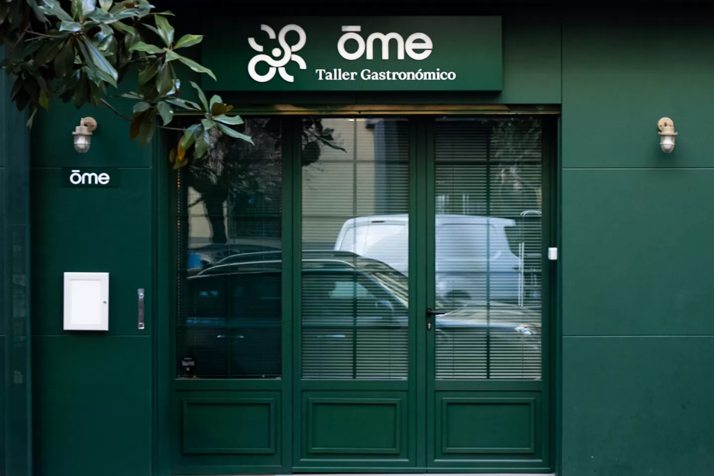 Fachada verde de ŌME Taller Gastronómico en el barrio de Salamanca de Madrid