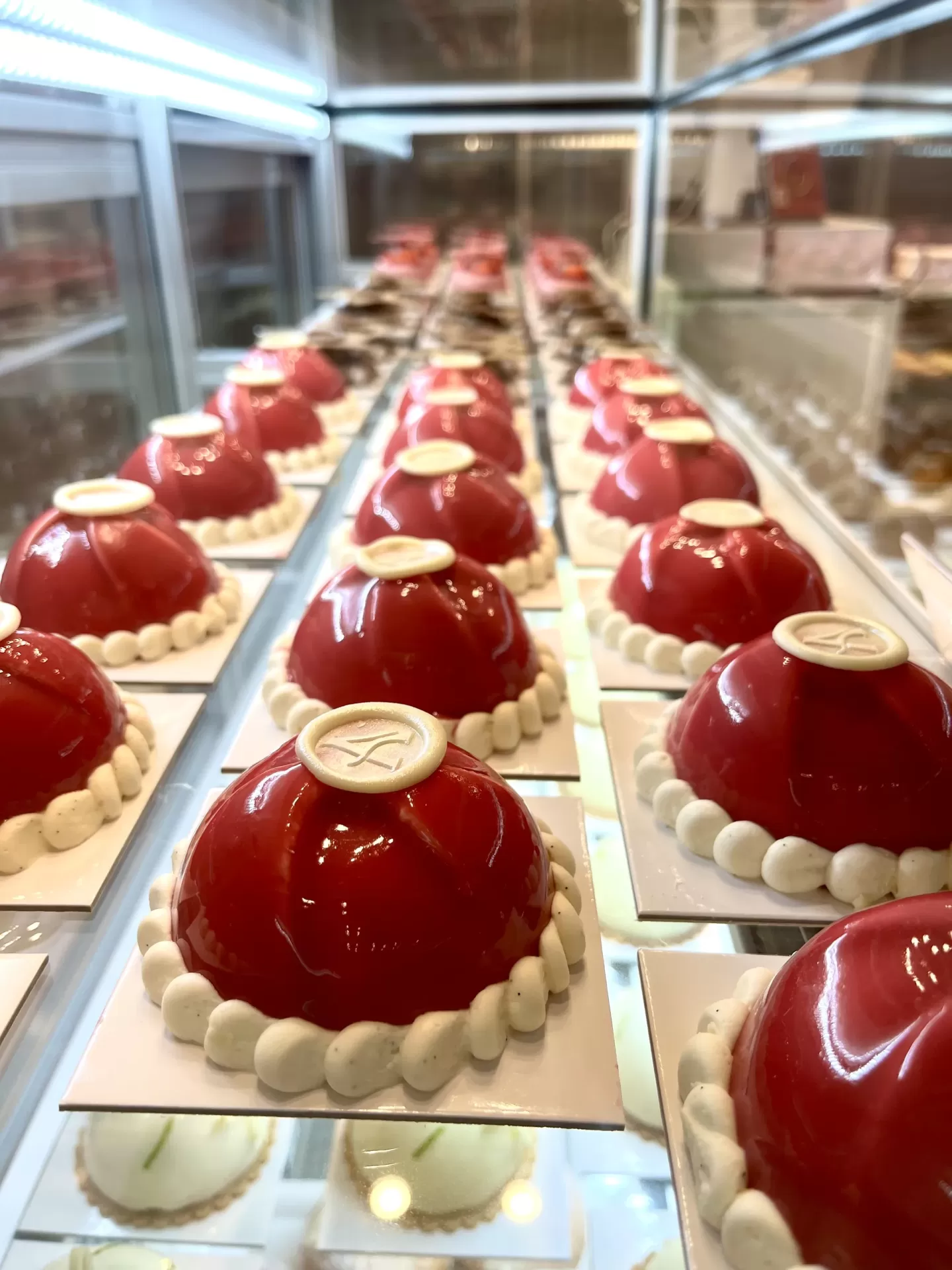 Pasteles individuales con glaseado rojo brillante en la vitrina de ITAMA