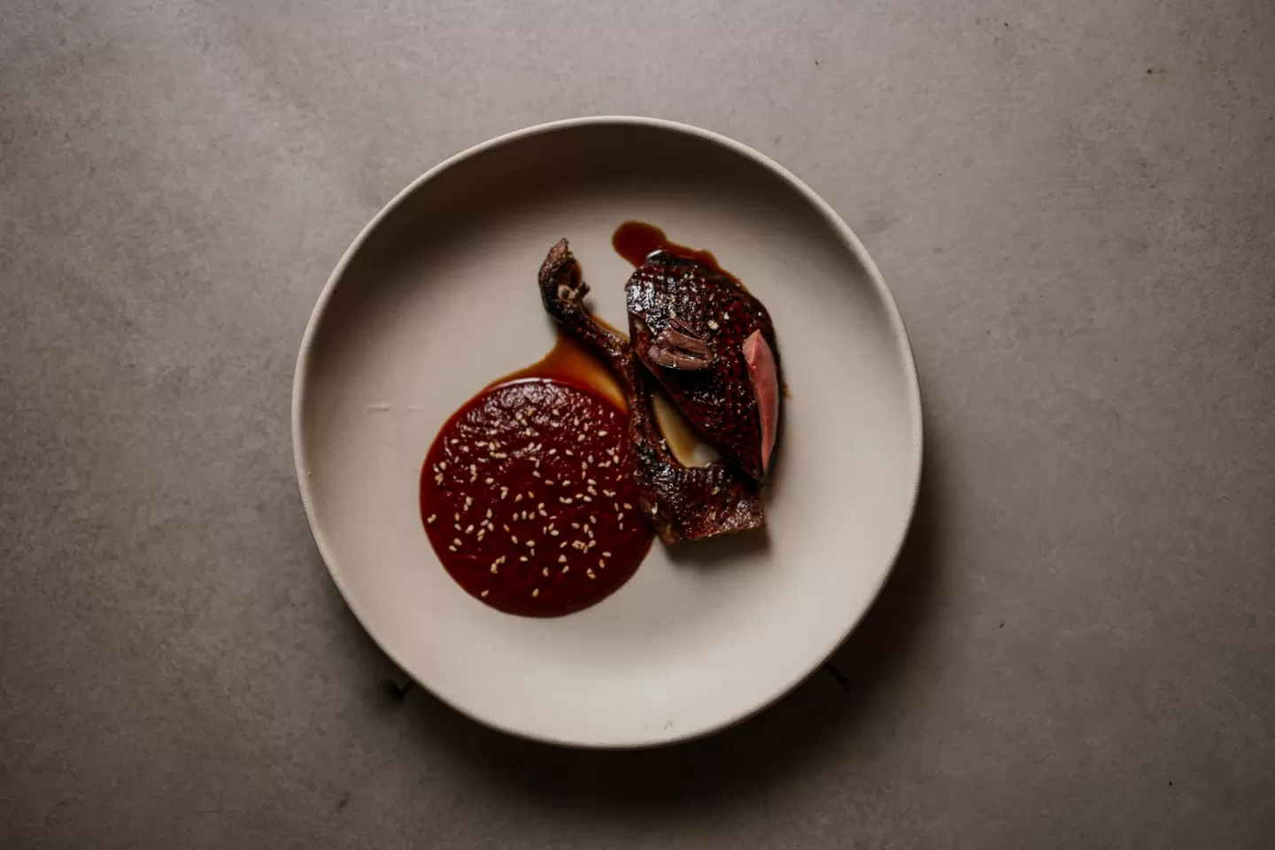 Codorniz lacada con salsa roja y sésamo servida en ŌME