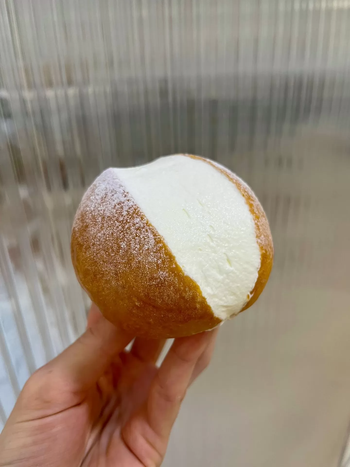Brioche relleno de nata montada de ITAMA sostenido en la mano